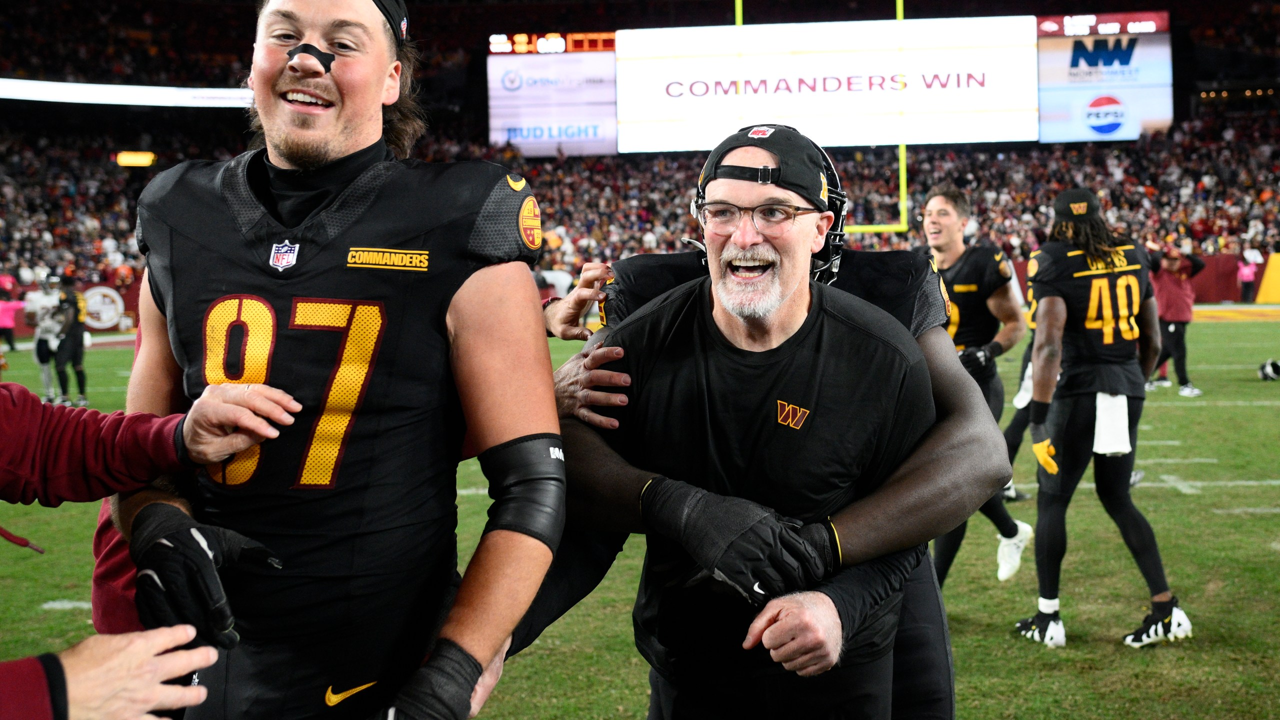 Washington Commanders head coach Dan Quinn and tight end John Bates (87) celebrate after the Commanders beat the Chicago Bears 18-15 in an NFL football game Sunday, Oct. 27, 2024, in Landover, Md. (AP Photo/Nick Wass)