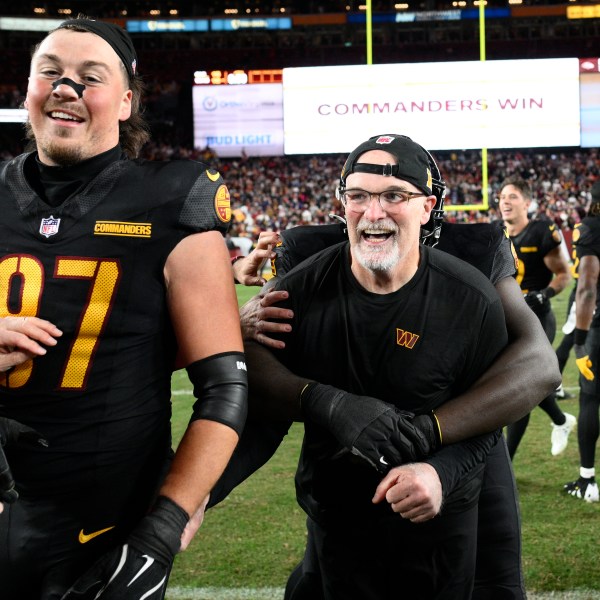 Washington Commanders head coach Dan Quinn and tight end John Bates (87) celebrate after the Commanders beat the Chicago Bears 18-15 in an NFL football game Sunday, Oct. 27, 2024, in Landover, Md. (AP Photo/Nick Wass)