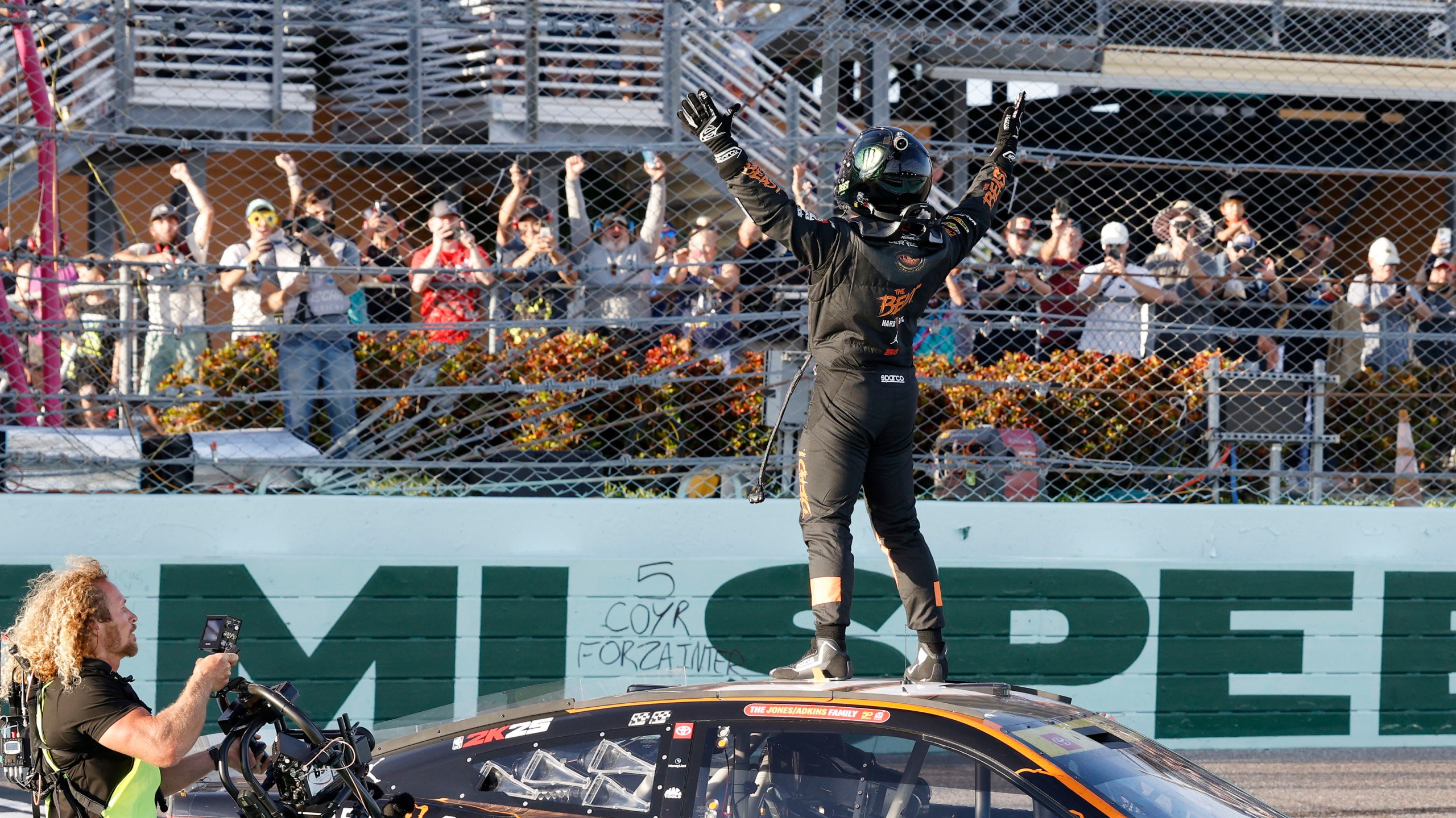 Tyler Reddick, front rifght, celebrates with fans at the finish line after winning a NASCAR Cup Series auto race at Homestead-Miami Speedway in Homestead, Fla., Sunday, Oct. 27, 2024. (AP Photo/Terry Renna)