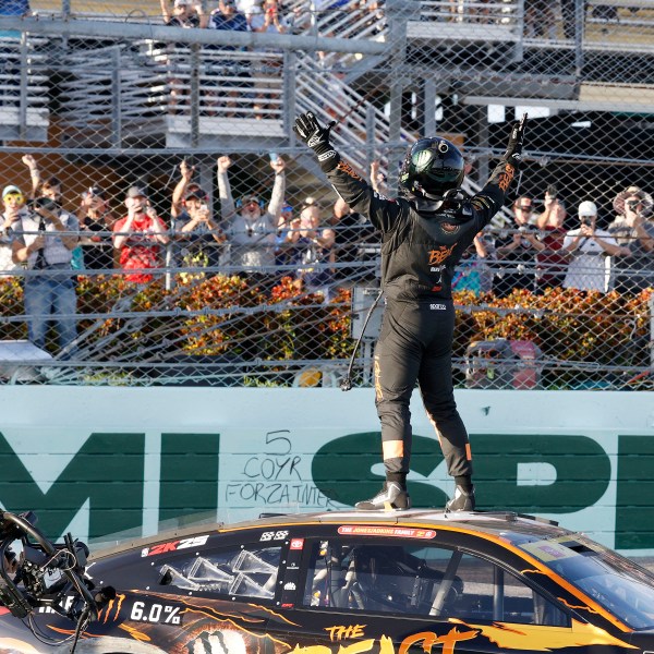 Tyler Reddick, front rifght, celebrates with fans at the finish line after winning a NASCAR Cup Series auto race at Homestead-Miami Speedway in Homestead, Fla., Sunday, Oct. 27, 2024. (AP Photo/Terry Renna)