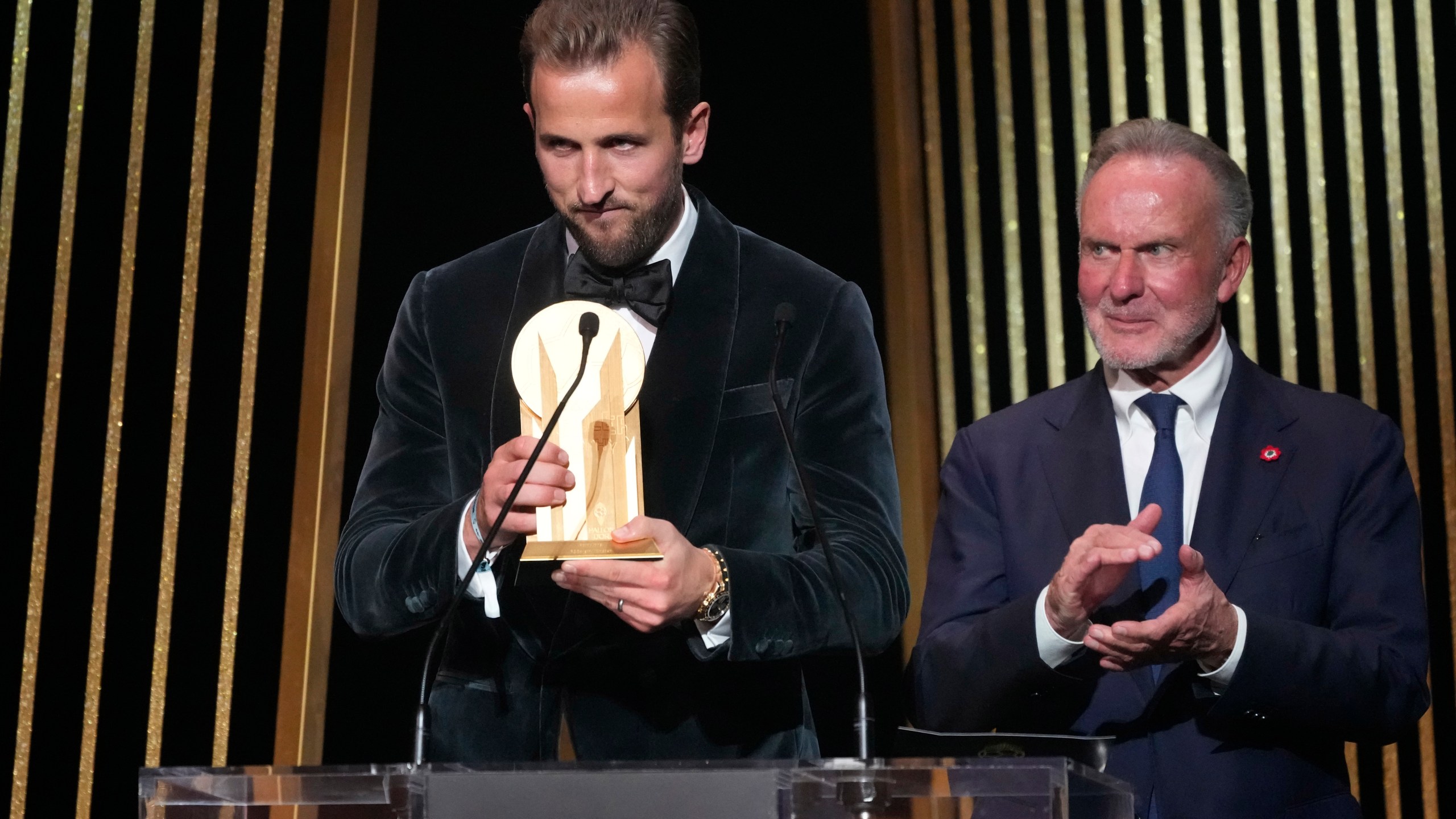 England's player Harry Kane, left, is flanked by former German player Karl-Heinz Rummenigge as he receives the Gerd Mueller trophy during the 68th Ballon d'Or (Golden Ball) award ceremony at Theatre du Chatelet in Paris, Monday, Oct. 28, 2024. (AP Photo/Michel Euler)