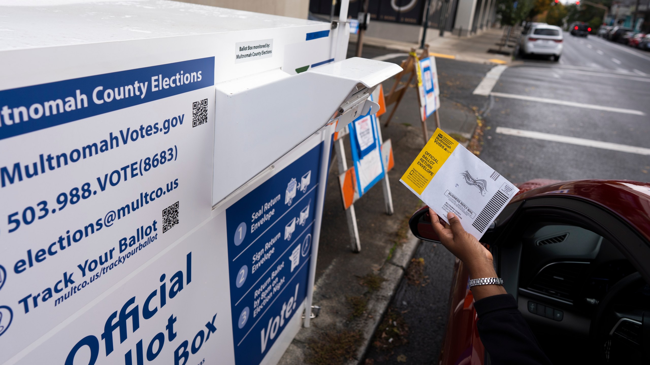 A voter drops off a ballot for the 2024 election in a newly installed drop box at the Multnomah County Elections Division office on Monday, Oct. 28, 2024, in Portland, Ore., after the pervious drop box was damaged. (AP Photo/Jenny Kane)