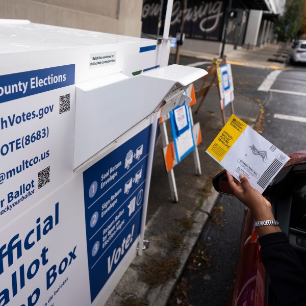 A voter drops off a ballot for the 2024 election in a newly installed drop box at the Multnomah County Elections Division office on Monday, Oct. 28, 2024, in Portland, Ore., after the pervious drop box was damaged. (AP Photo/Jenny Kane)