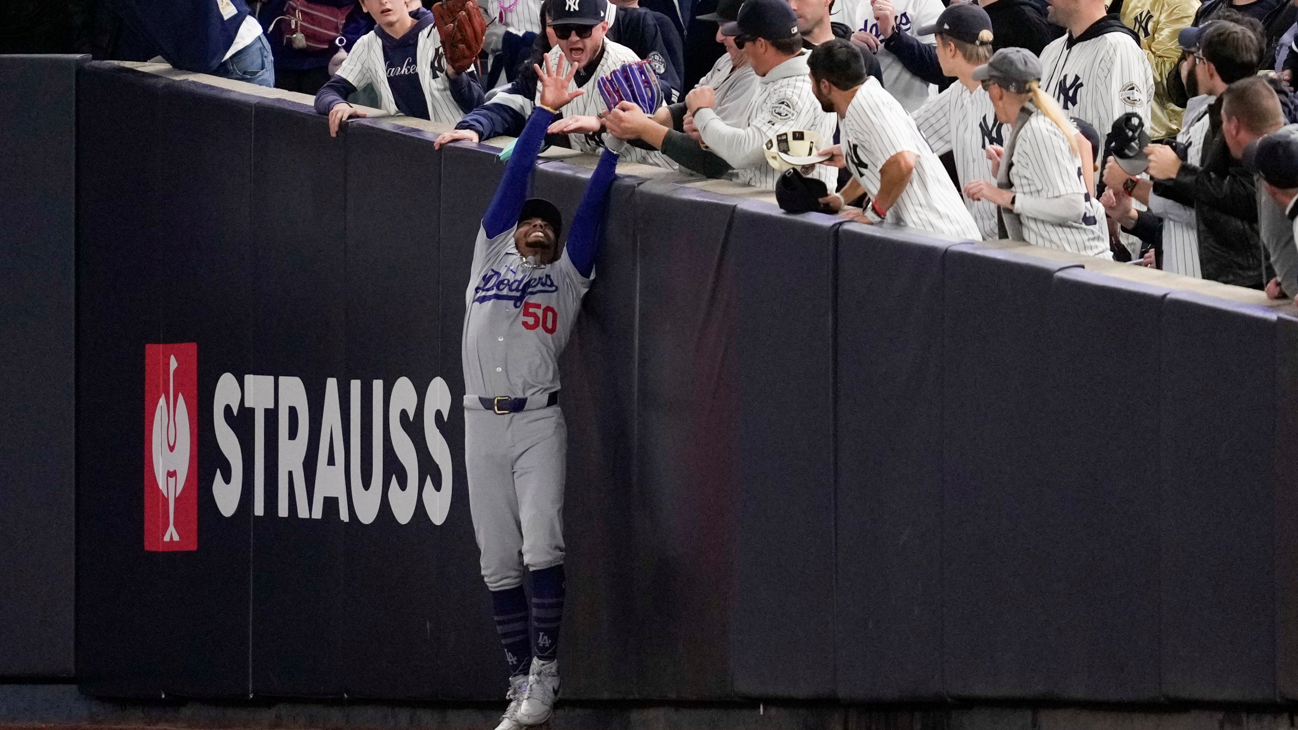 Fans interfere with a foul ball caught by Los Angeles Dodgers right fielder Mookie Betts during the first inning in Game 4 of the baseball World Series against the New York Yankees, Tuesday, Oct. 29, 2024, in New York. (AP Photo/Ashley Landis)