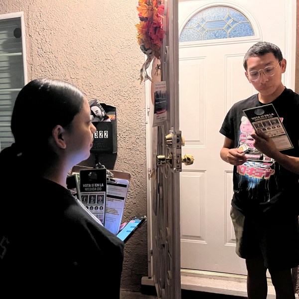 Genesis Lopez, 21, speaks with Santa Ana, Calif. resident Eduardo Entimio, 23, on Wednesday, Oct. 23, 2024, about Measure DD, which would allow noncitizens to vote in local elections. (AP Photo/Jaimie Ding)