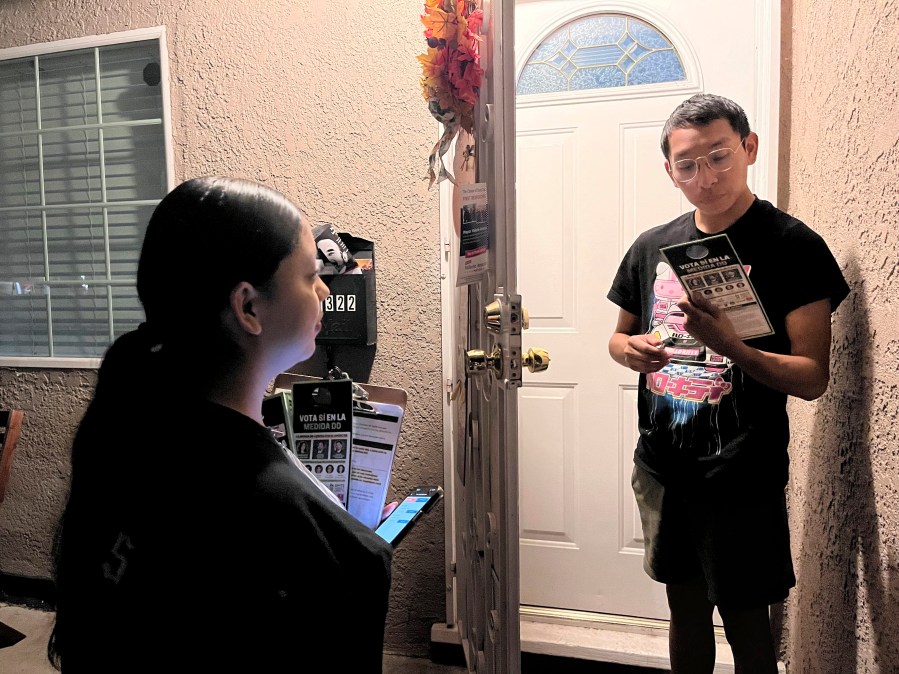 Genesis Lopez, 21, speaks with Santa Ana, Calif. resident Eduardo Entimio, 23, on Wednesday, Oct. 23, 2024, about Measure DD, which would allow noncitizens to vote in local elections. (AP Photo/Jaimie Ding)