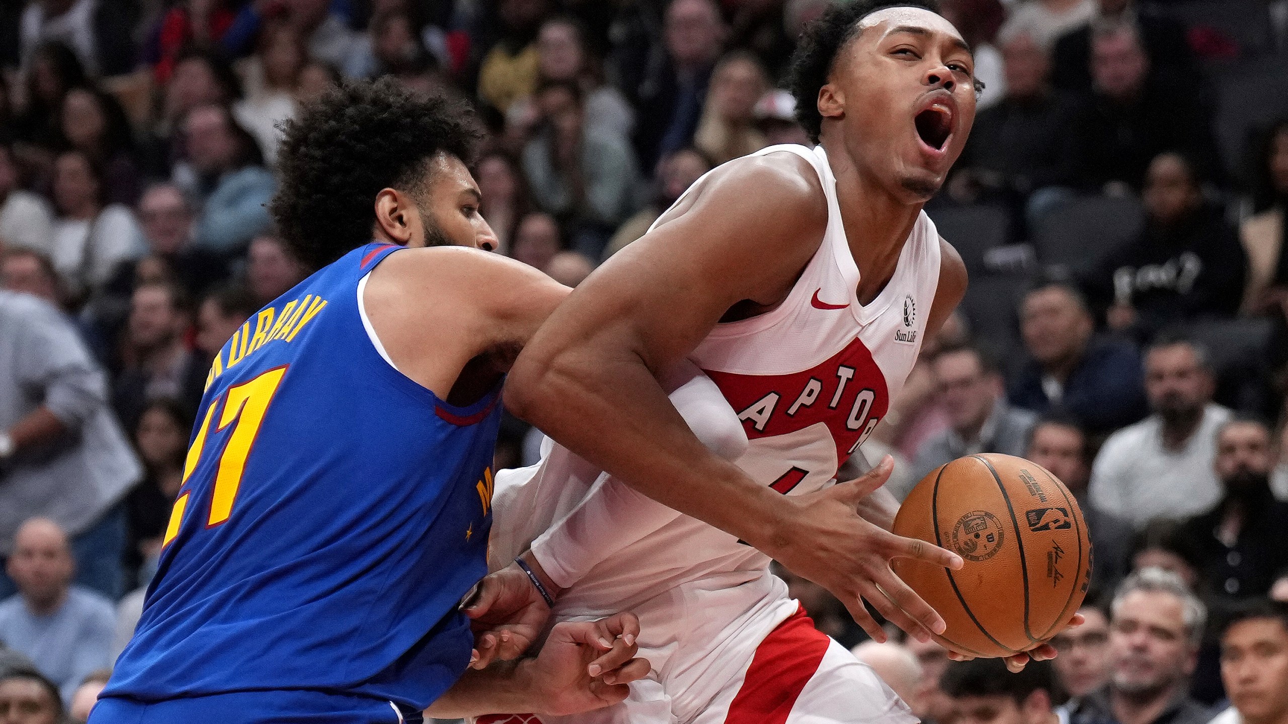 Toronto Raptors forward Scottie Barnes, right, reacts as he drives into Denver Nuggets guard Jamal Murray, left, during first-half NBA basketball game action in Toronto, Monday, Oct. 28, 2024. (Nathan Denette/The Canadian Press via AP)