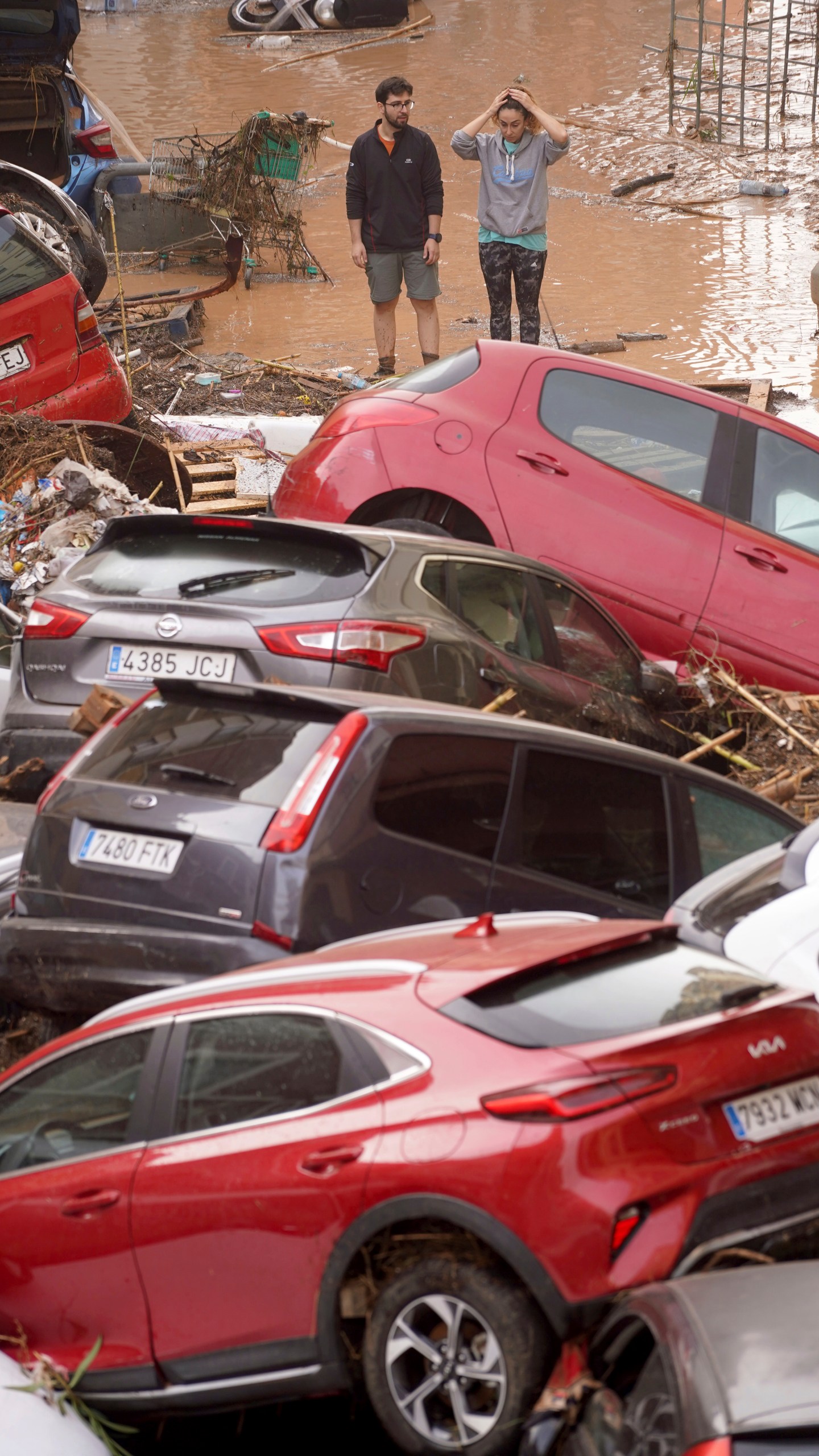 Residents look at cars piled up after being swept away by floods in Valencia, Spain, Wednesday, Oct. 30, 2024. (AP Photo/Alberto Saiz)