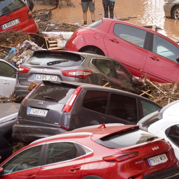 Residents look at cars piled up after being swept away by floods in Valencia, Spain, Wednesday, Oct. 30, 2024. (AP Photo/Alberto Saiz)