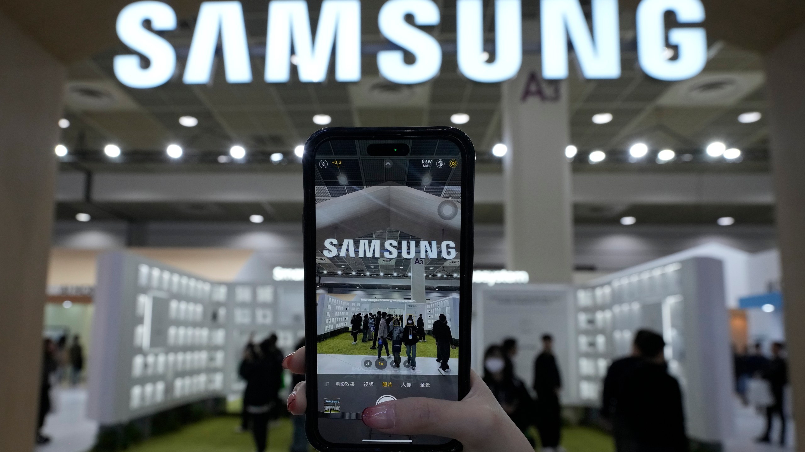 A visitor takes a picture of the logo of Samsung Electronics at its booth during The Semiconductor Exhibition 2024 at the COEX convention center in Seoul, South Korea, Wednesday, Oct. 23, 2024. (AP Photo/Ahn Young-joon)