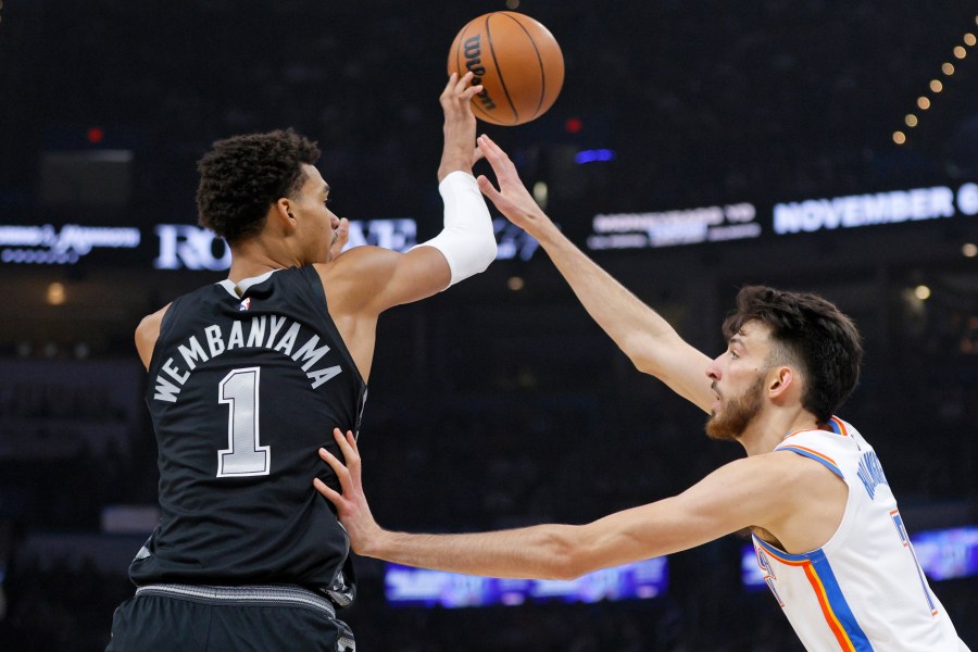 San Antonio Spurs center Victor Wembanyama (1) passes the ball over Oklahoma City Thunder forward Chet Holmgren, right, during the first half of an NBA basketball game Wednesday, Oct. 30, 2024, in Oklahoma City. (AP Photo/Nate Billings)