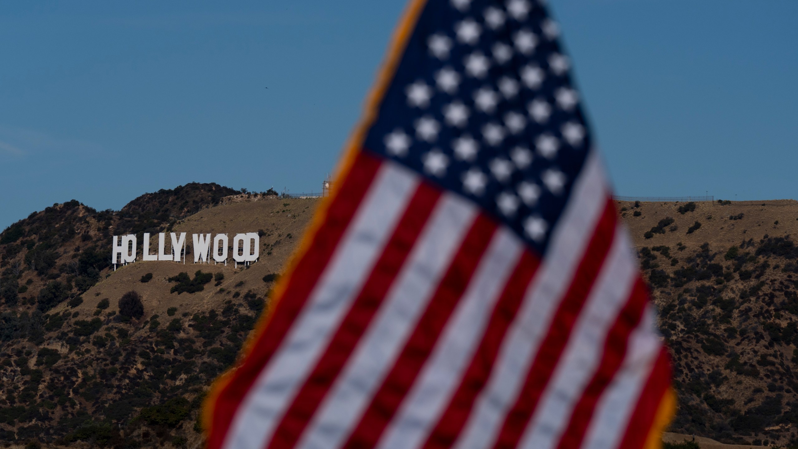 With the Hollywood sign in the background, an American flag stands during a naturalization ceremony at Griffith Observatory in Los Angeles, Monday, Oct. 21, 2024. (AP Photo/Jae C. Hong)