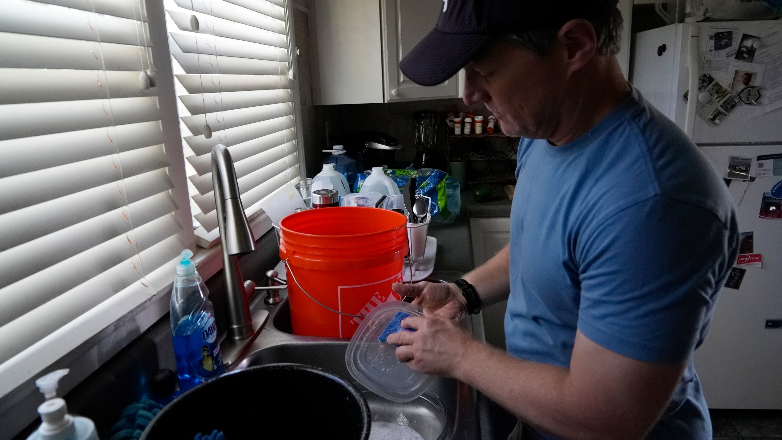 FILE - Travis Edwards captures excess water while cleaning dishes on Oct. 3, 2024, in Asheville, N.C. (AP Photo/Brittany Peterson, File)