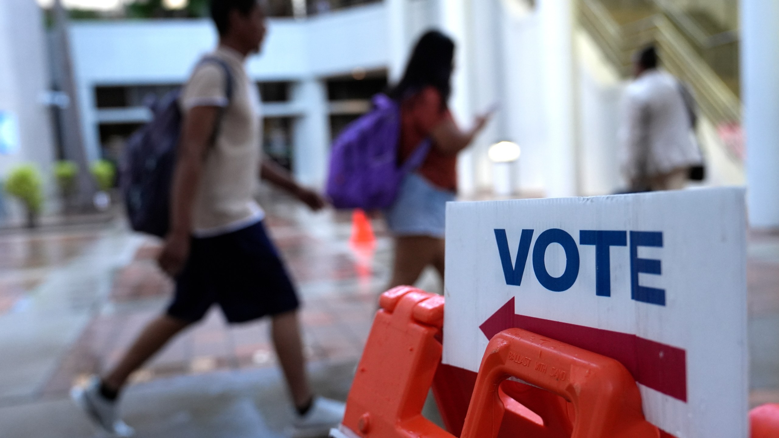 People walk past a Vote sign on the first day of early voting in the general election, Oct. 21, 2024, in Miami. (AP Photo/Lynne Sladky, File)