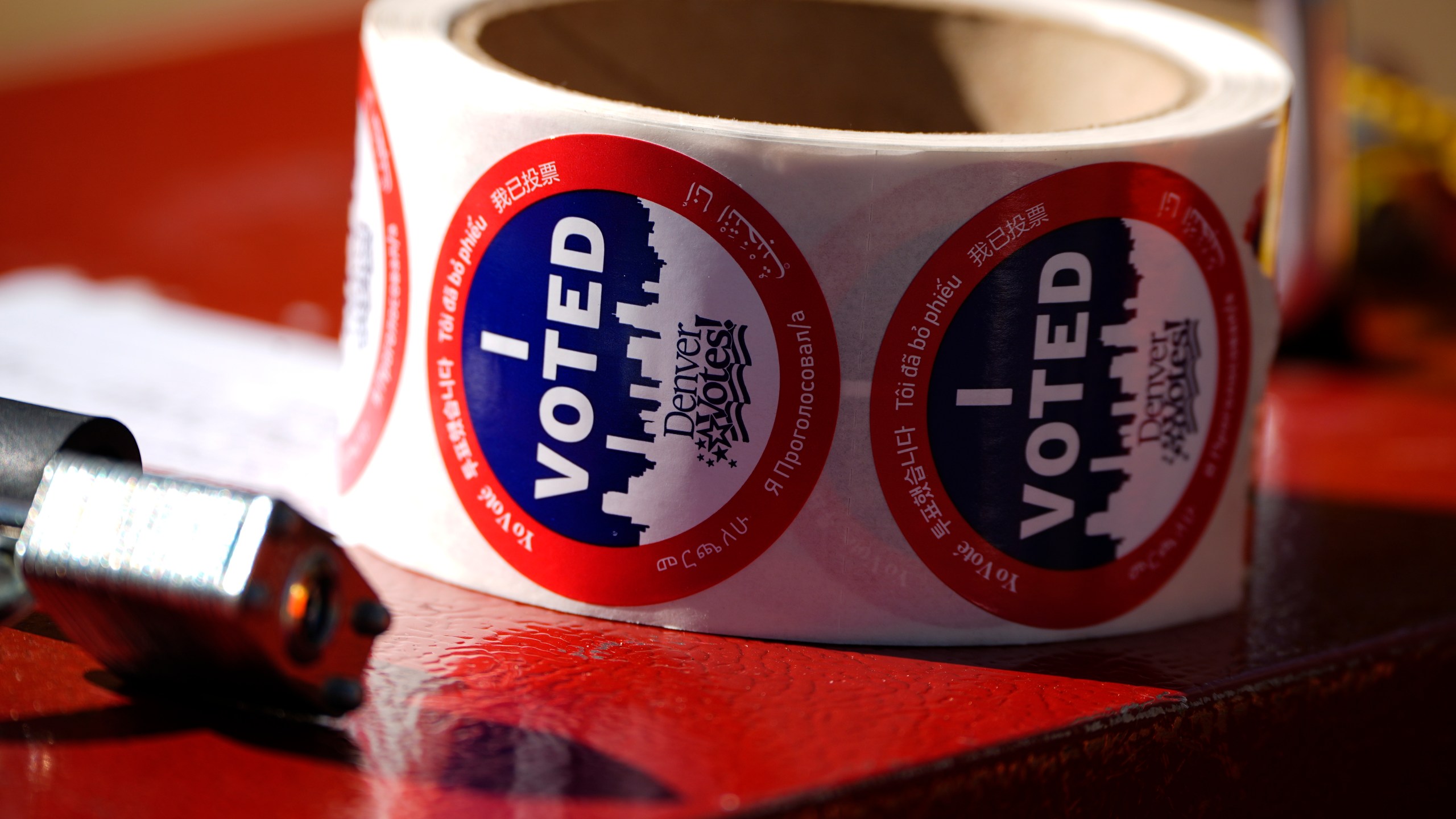 Stickers for voters sit in a roll on a ballot box at a voting drop-off location Friday, Oct. 25, 2024, in Washington Park in Denver. (AP Photo/David Zalubowski)