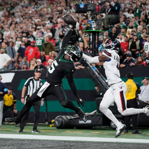 New York Jets wide receiver Garrett Wilson (5) catches a pass for a touchdown as Houston Texans cornerback Kamari Lassiter (4) defends during the second half of an NFL football game Thursday, Oct. 31, 2024, in East Rutherford, N.J. (AP Photo/Seth Wenig)