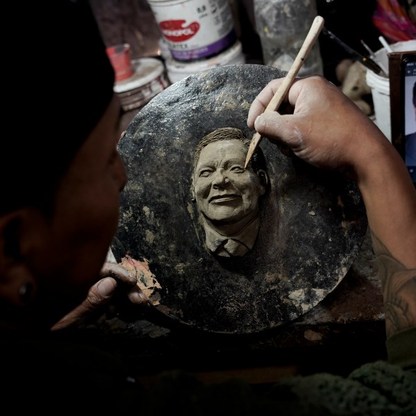 Artisan William Luna creates a mask of a loved one for the Mendoza family to adorn a piece of tantawawa, a sweet bread traditional for Day of the Dead celebrations, in La Paz, Bolivia, Thursday, Oct. 31, 2024. (AP Photo/Freddy Barragan)