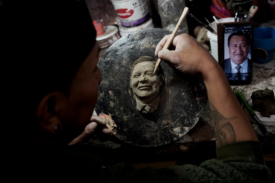 Artisan William Luna creates a mask of a loved one for the Mendoza family to adorn a piece of tantawawa, a sweet bread traditional for Day of the Dead celebrations, in La Paz, Bolivia, Thursday, Oct. 31, 2024. (AP Photo/Freddy Barragan)