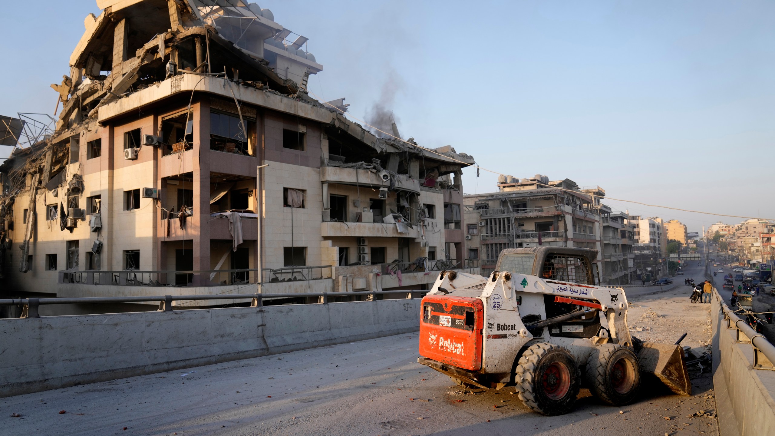 A municipality worker uses a skid steer loader to reopen a bridge closed by the rubble of a destroyed building that was hit by an Israeli airstrike on Dahiyeh, in the southern suburb of Beirut, Lebanon, Friday, Nov. 1, 2024. (AP Photo/Hussein Malla)