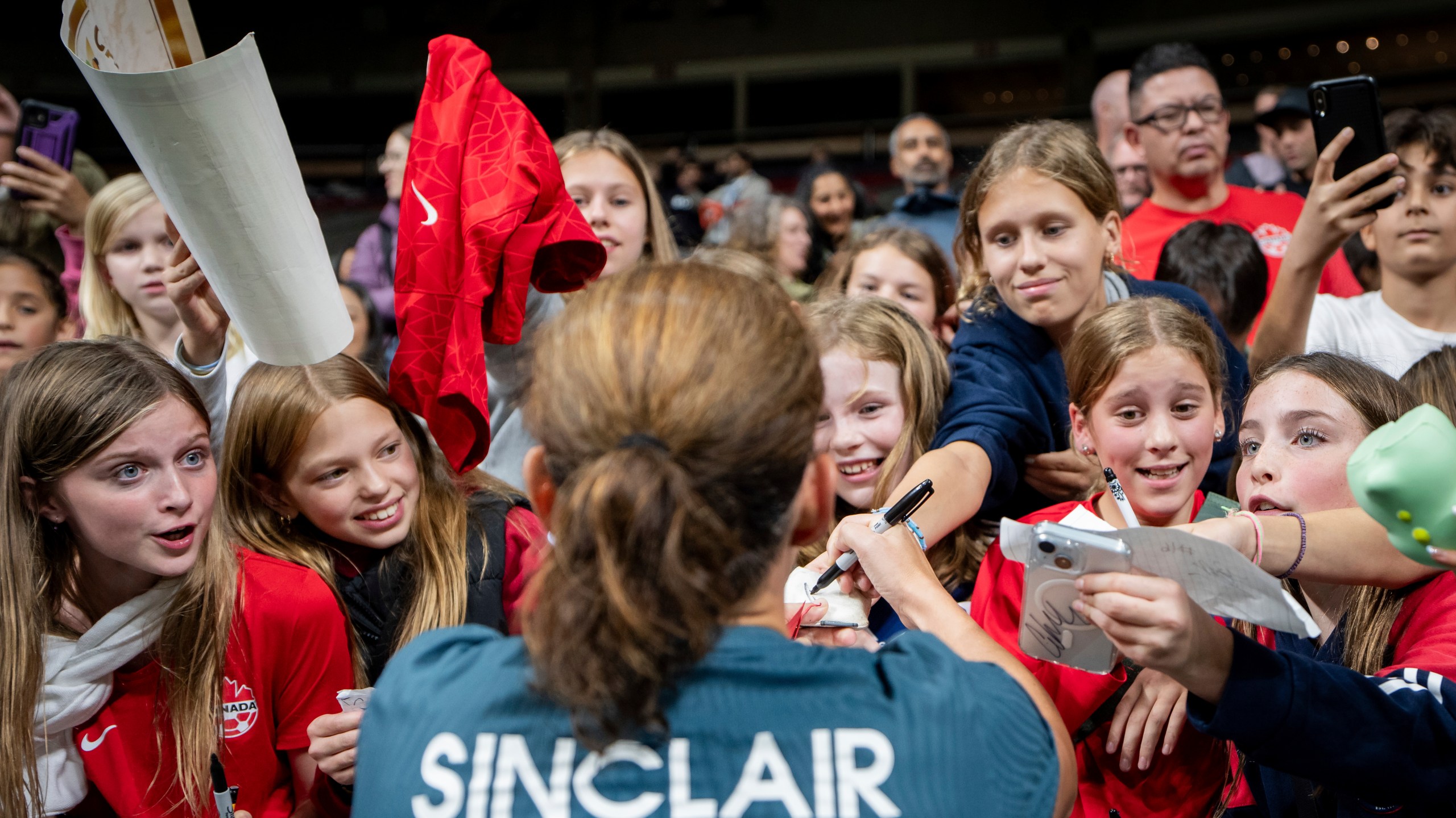 Portland Thorns FC's Christine Sinclair signs autographs for fans after a CONCACAF W Champions Cup match against the Vancouver Whitecaps in Vancouver, British Columbia, Tuesday, Oct. 15, 2024. (Ethan Cairns/The Canadian Press via AP)