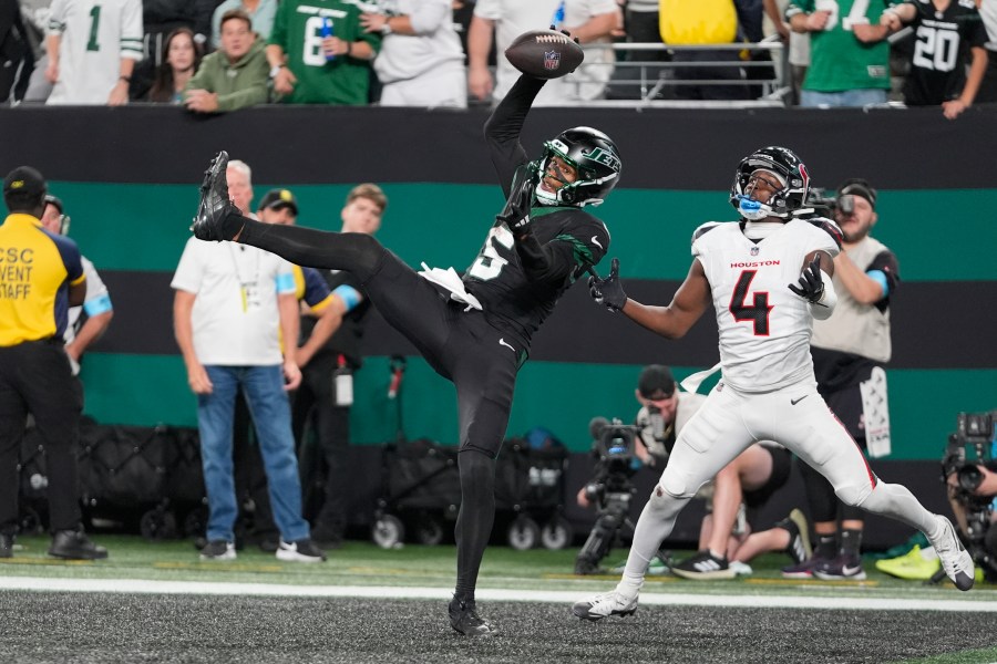 CORRECTS BYLINE - New York Jets wide receiver Garrett Wilson (5) catches a pass for a touchdown as Houston Texans cornerback Kamari Lassiter (4) defends during the second half of an NFL football game Thursday, Oct. 31, 2024, in East Rutherford, N.J. (AP Photo/Frank Franklin II)