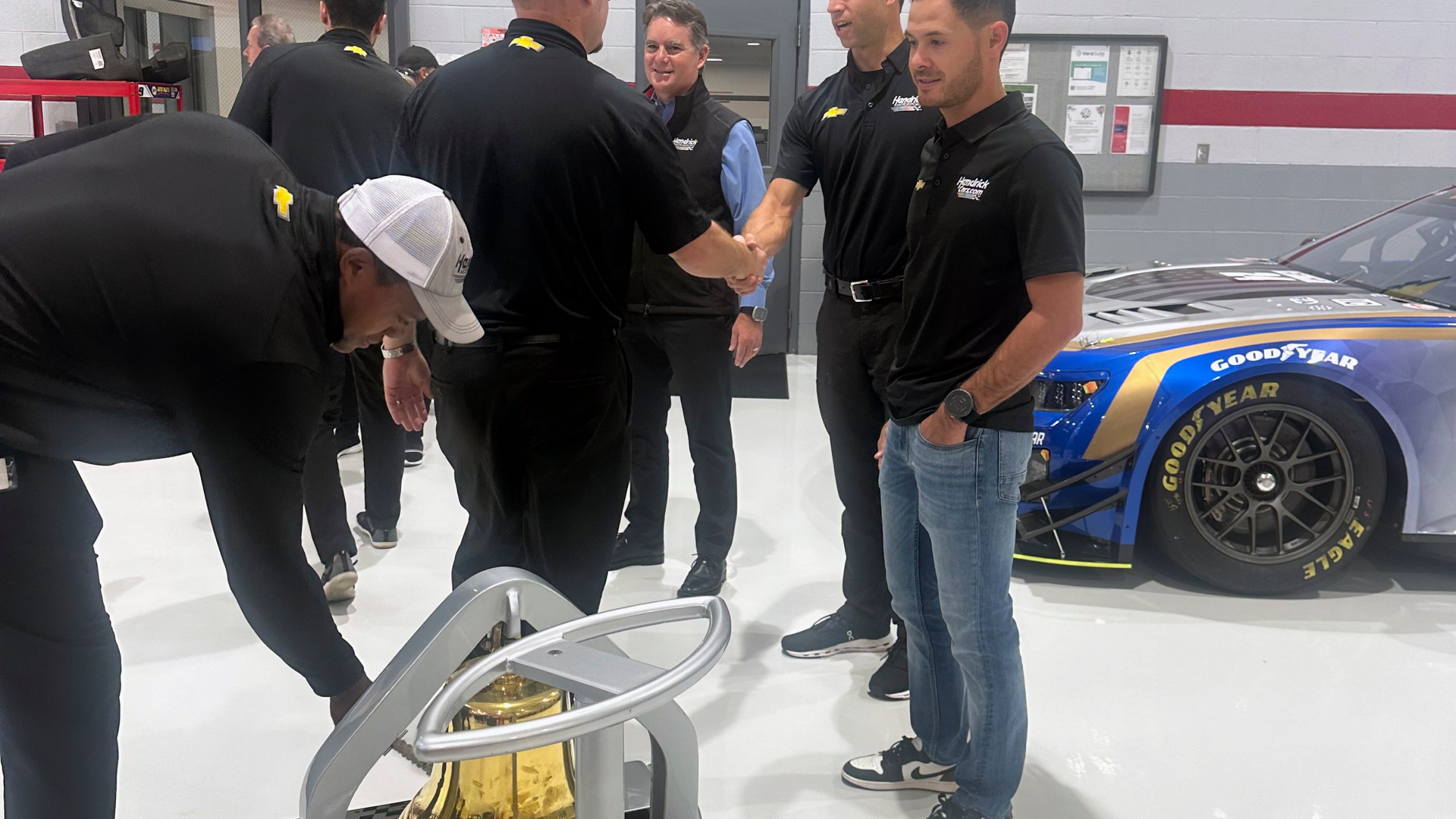 Hendrick Motorsports vice chairman Jeff Gordon, center rear, crew chief Cliff Daniels, second from right, and Kyle Larson shake hands with Hendrick Motorsports teammates during the victory bell ringing ceremony for Larson’s win at Bristol Motor Speedway, Oct. 9, 2024, at Hendrick Motorsports in Charlotte, N.C. (AP Photo/Jenna Fryer)