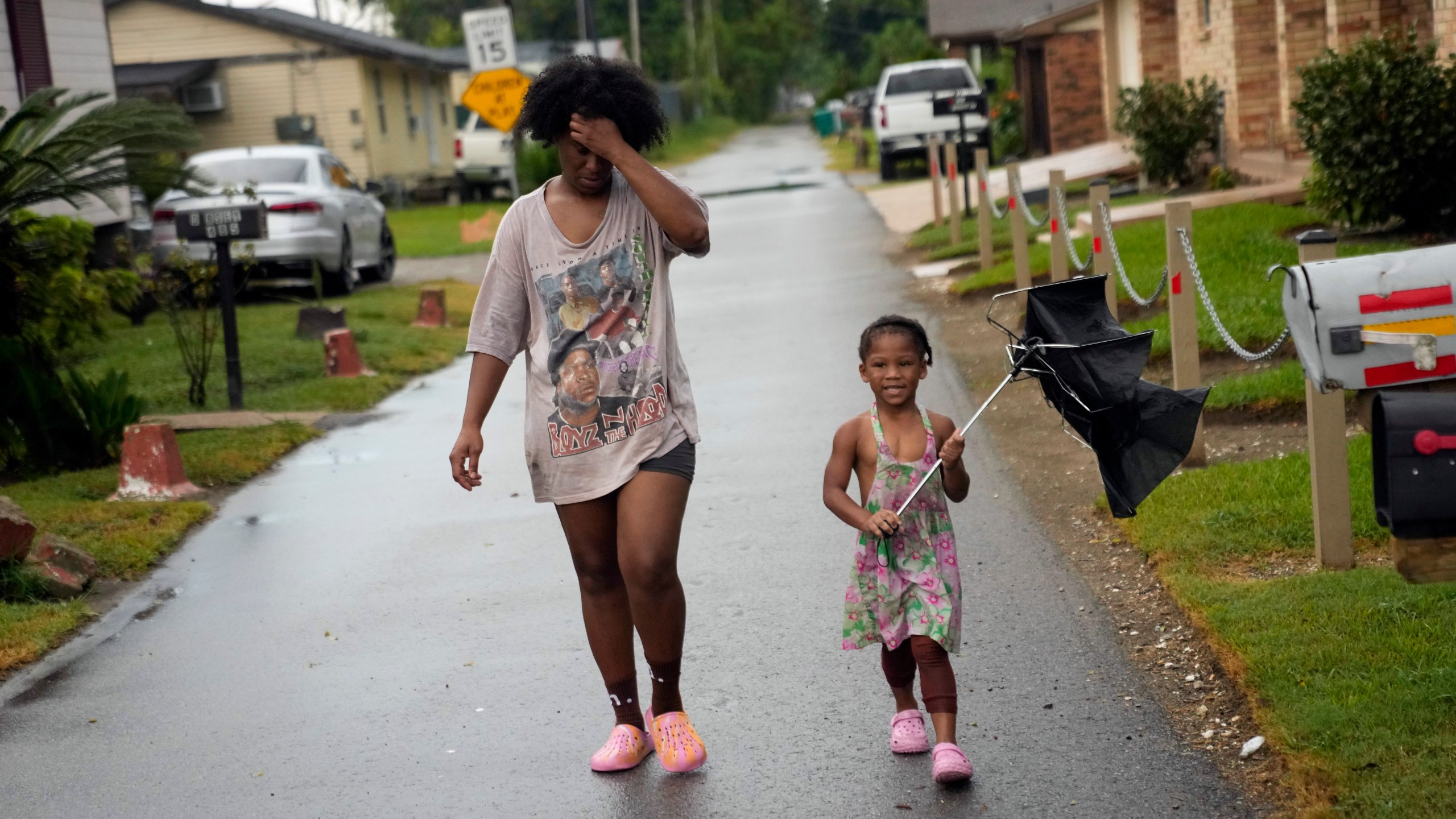 Residents walk down the street in the historic Elkinsville section of in St. Rose, La., Friday, Aug. 16, 2024. (AP Photo/Gerald Herbert)