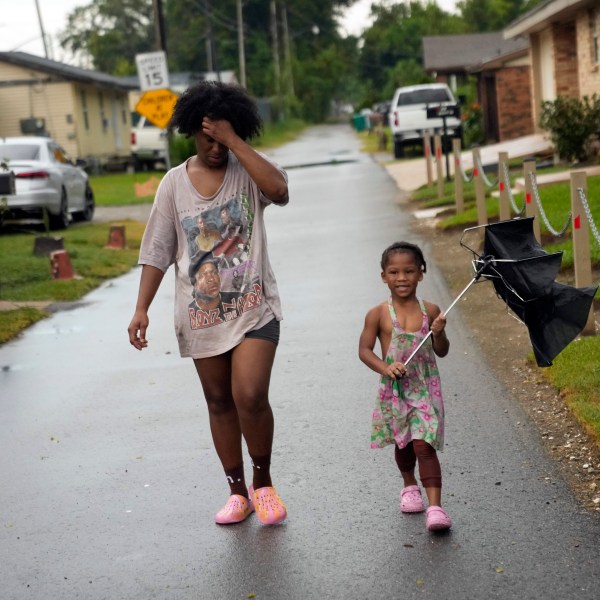 Residents walk down the street in the historic Elkinsville section of in St. Rose, La., Friday, Aug. 16, 2024. (AP Photo/Gerald Herbert)