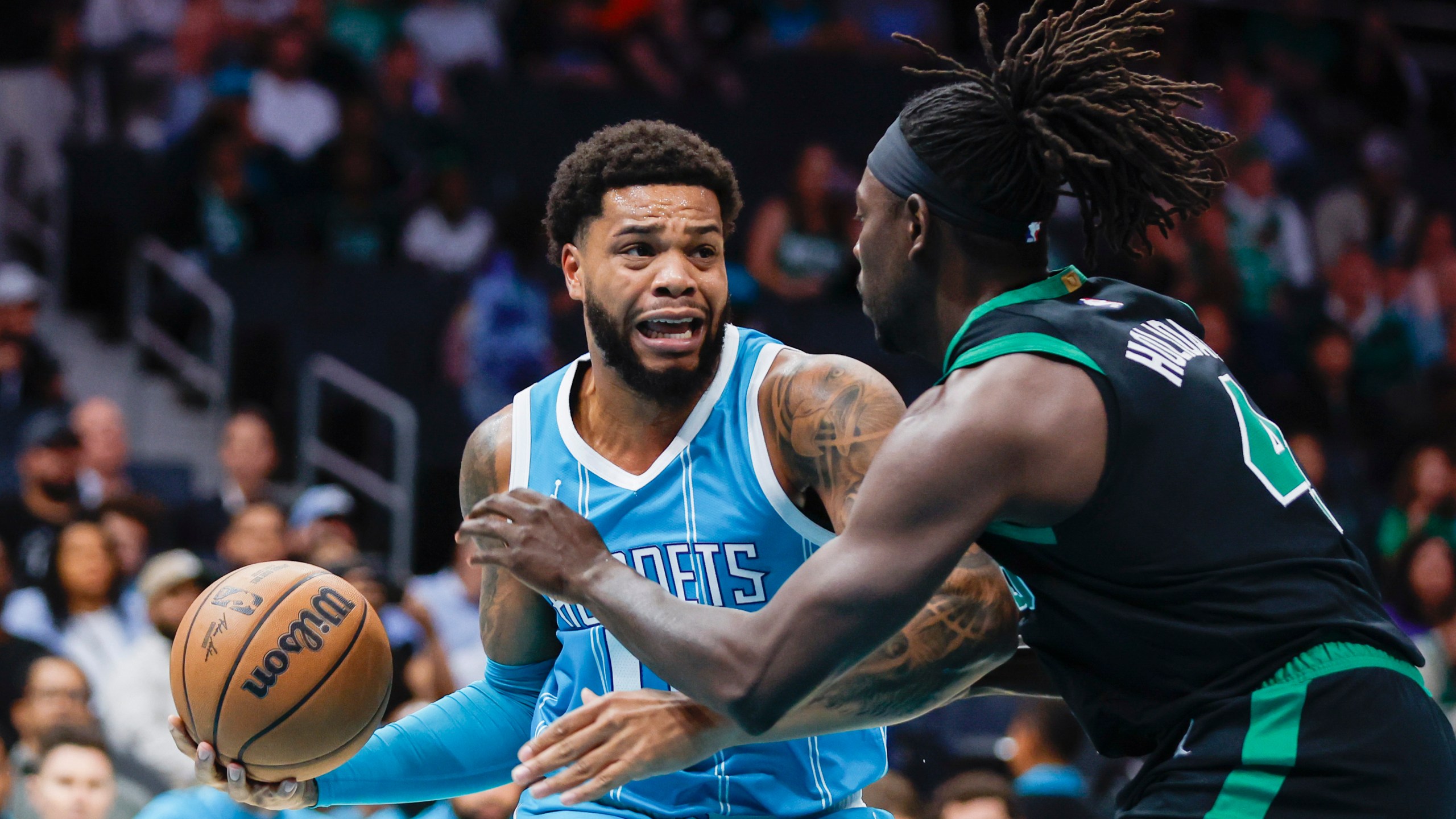 Charlotte Hornets forward Miles Bridges, left, drives against Boston Celtics guard Jrue Holiday during the first quarter of an NBA basketball game in Charlotte, N.C., Friday, Nov. 1, 2024. (AP Photo/Nell Redmond)