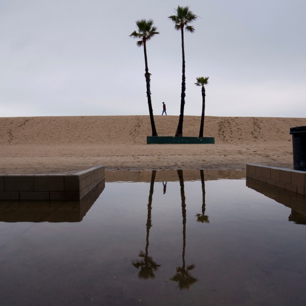 FILE - A person walks along the beach with flooding along the boardwalk Thursday, Feb. 1, 2024 in Seal Beach, Calif. (AP Photo/Eric Thayer, file)