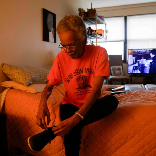 Bernadine Gibson, 82, puts on shoes as she prepares to see renovations being done to the building her family has lived in for 27 years, Monday, Nov. 18, 2024, in Chicago. (AP Photo/Erin Hooley)