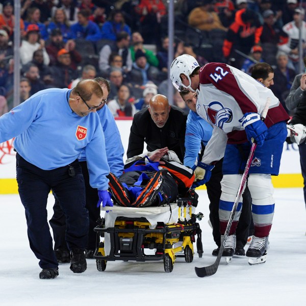 Colorado Avalanche's Josh Manson (42), right, talks to referee Mitch Dunning, center, as Dunning is stretchered off the ice after an injury during the first period of an NHL hockey game between the Philadelphia Flyers and the Avalanche, Monday, Nov. 18, 2024, in Philadelphia. (AP Photo/Derik Hamilton)