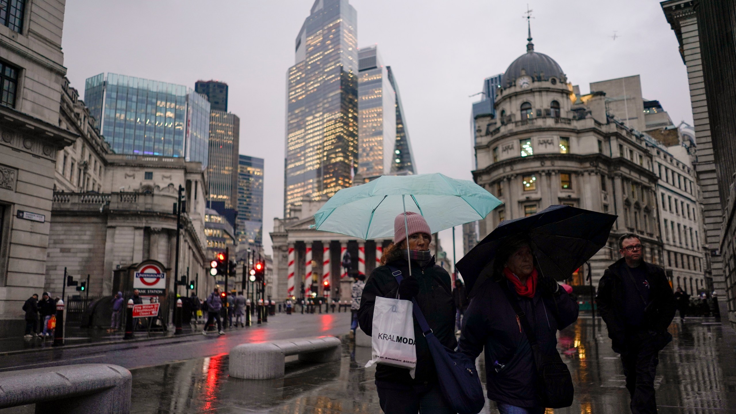 People hold umbrellas as they walk in front of the Bank of England, at the start of a week that is set to see the temperatures drop, in London, Monday, Nov. 18, 2024. (AP Photo/Alberto Pezzali)