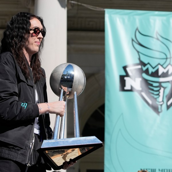 New York Liberty Breanna Stewart places the championship trophy on a table as she arrives on stage during a ceremony after a parade in honor of the Liberty's WNBA basketball championship at City Hall in New York, Thursday, Oct. 24, 2024. (AP Photo/Seth Wenig)