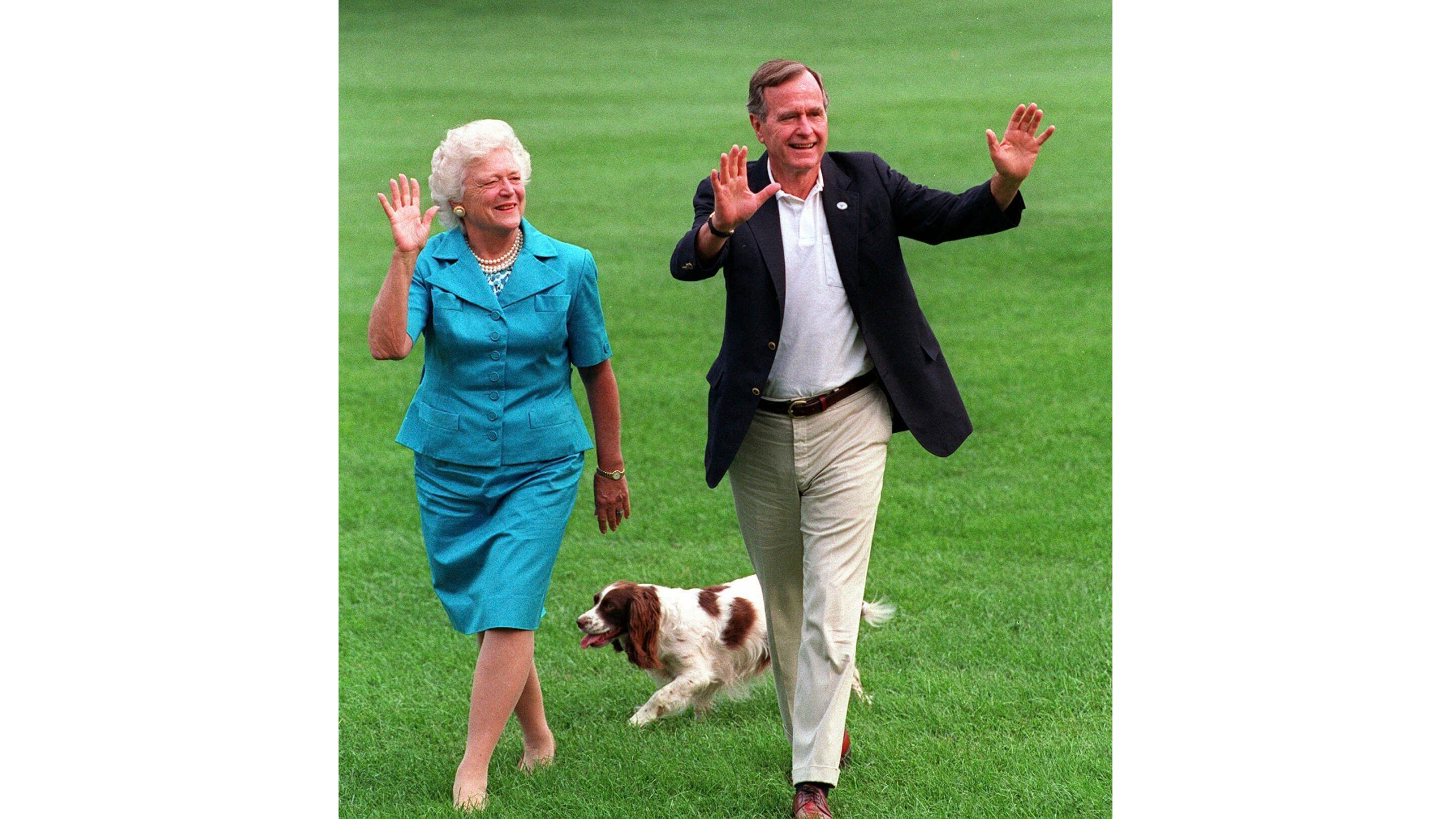 FILE- President Bush, right, and first lady Barbara Bush walking with their dog Millie across the South Lawn as they return to the White House, Aug. 24, 1992. (AP Photo/Scott Applewhite, File)