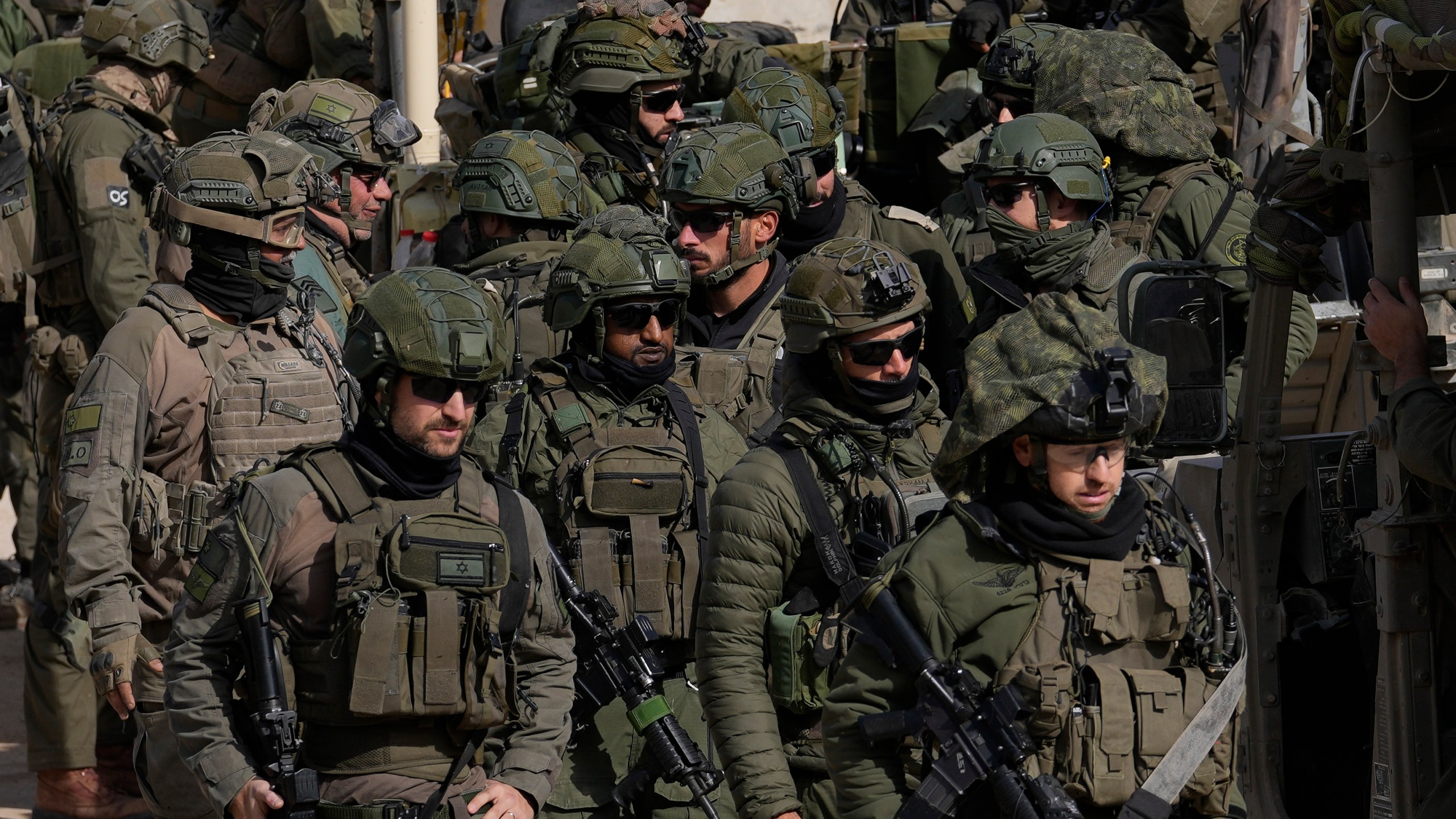 Israeli soldiers stand next to armoured vehicles before crossing the security fence, moving towards the so-called Alpha Line that separates the Israeli-controlled Golan Heights from Syria, in the town of Majdal Shams, Thursday, Dec. 12, 2024. (AP Photo/Matias Delacroix)