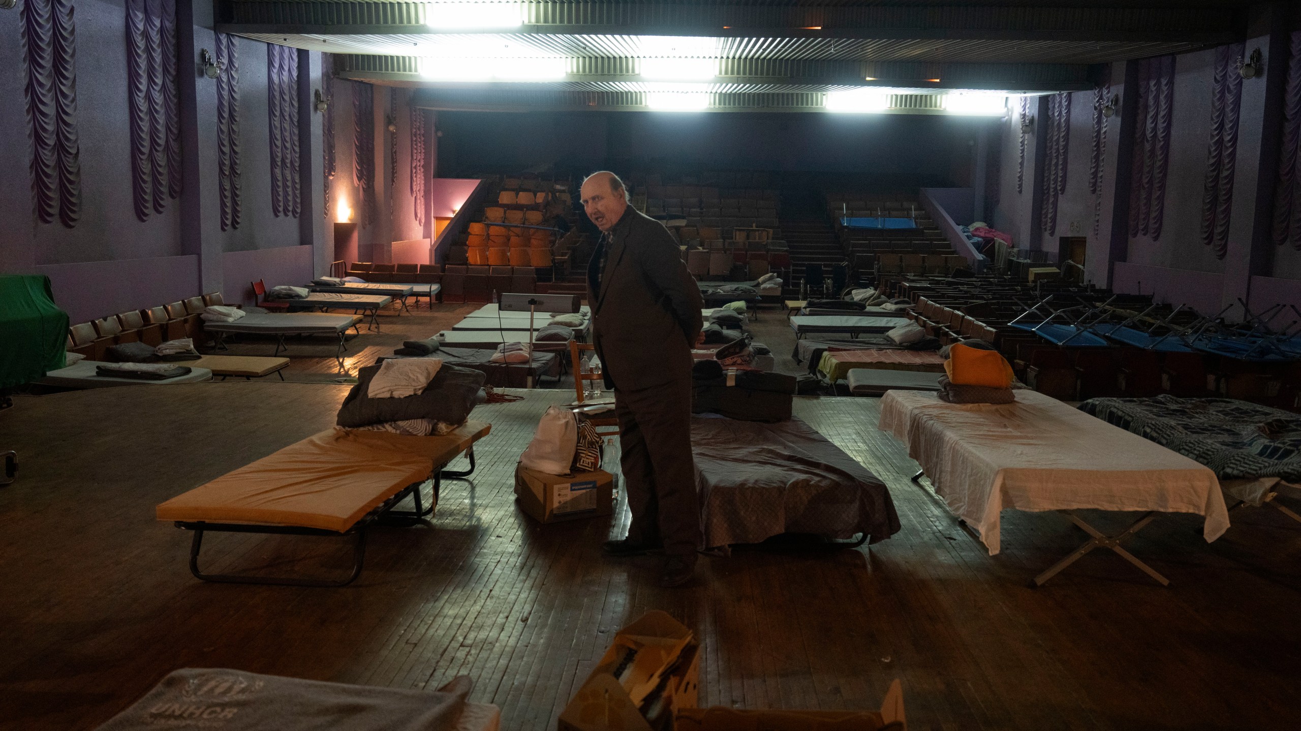 A man waits for evacuation to western Ukraine as he stands by a bed in a city theatre that hosts refugees running from Russian offensive in the Donetsk region, in Pavlohrad, Dnipropetrovsk region, Ukraine, Thursday, Dec. 12, 2024.(AP Photo/Efrem Lukatsky)