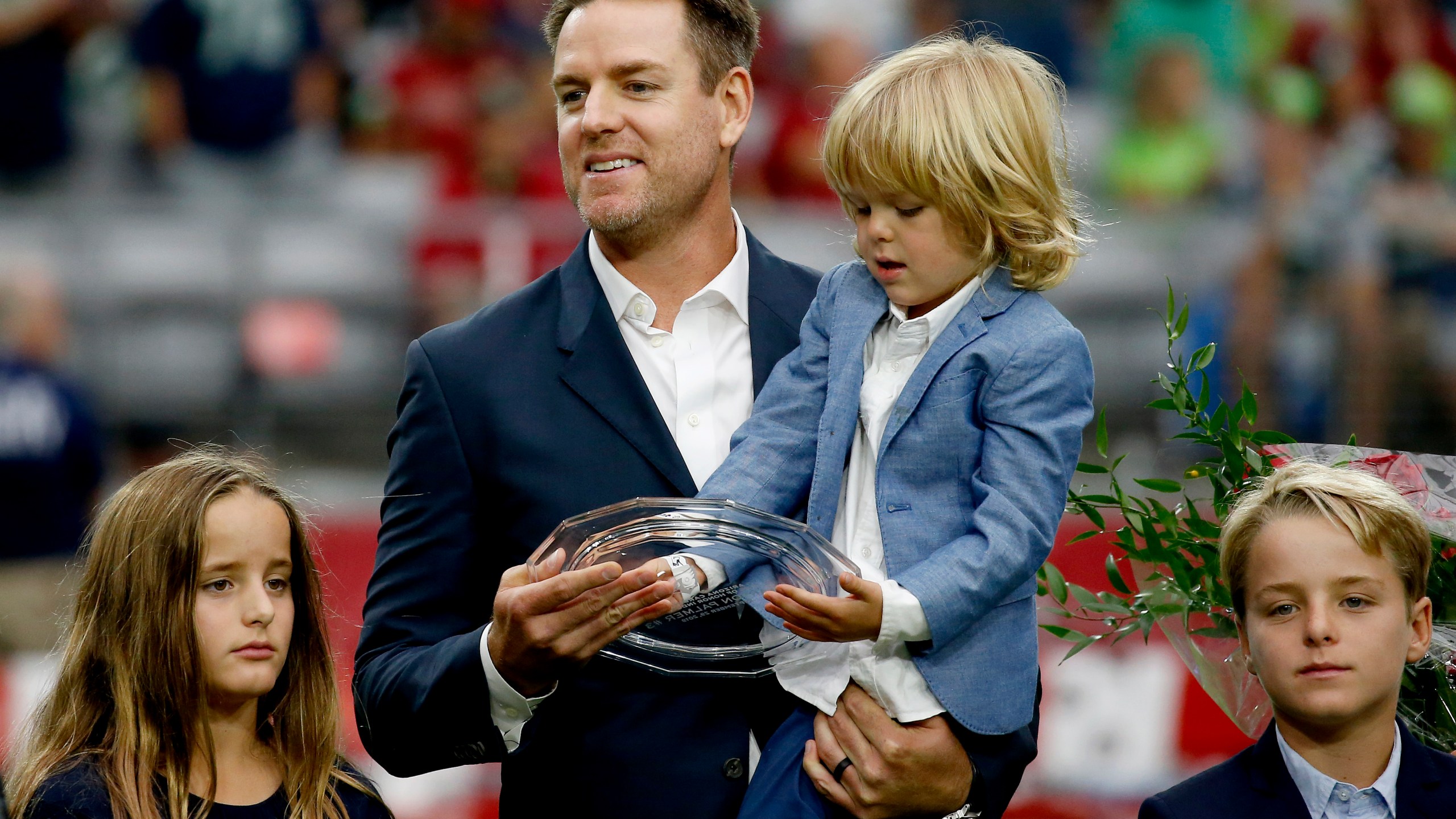 FILE - Former Arizona Cardinals quarterback Carson Palmer stands with his family after being added to the Cardinals ring of honor during a halftime game in Glendale, Ariz., Sept. 29, 2019. (AP Photo/Ross D. Franklin, file)