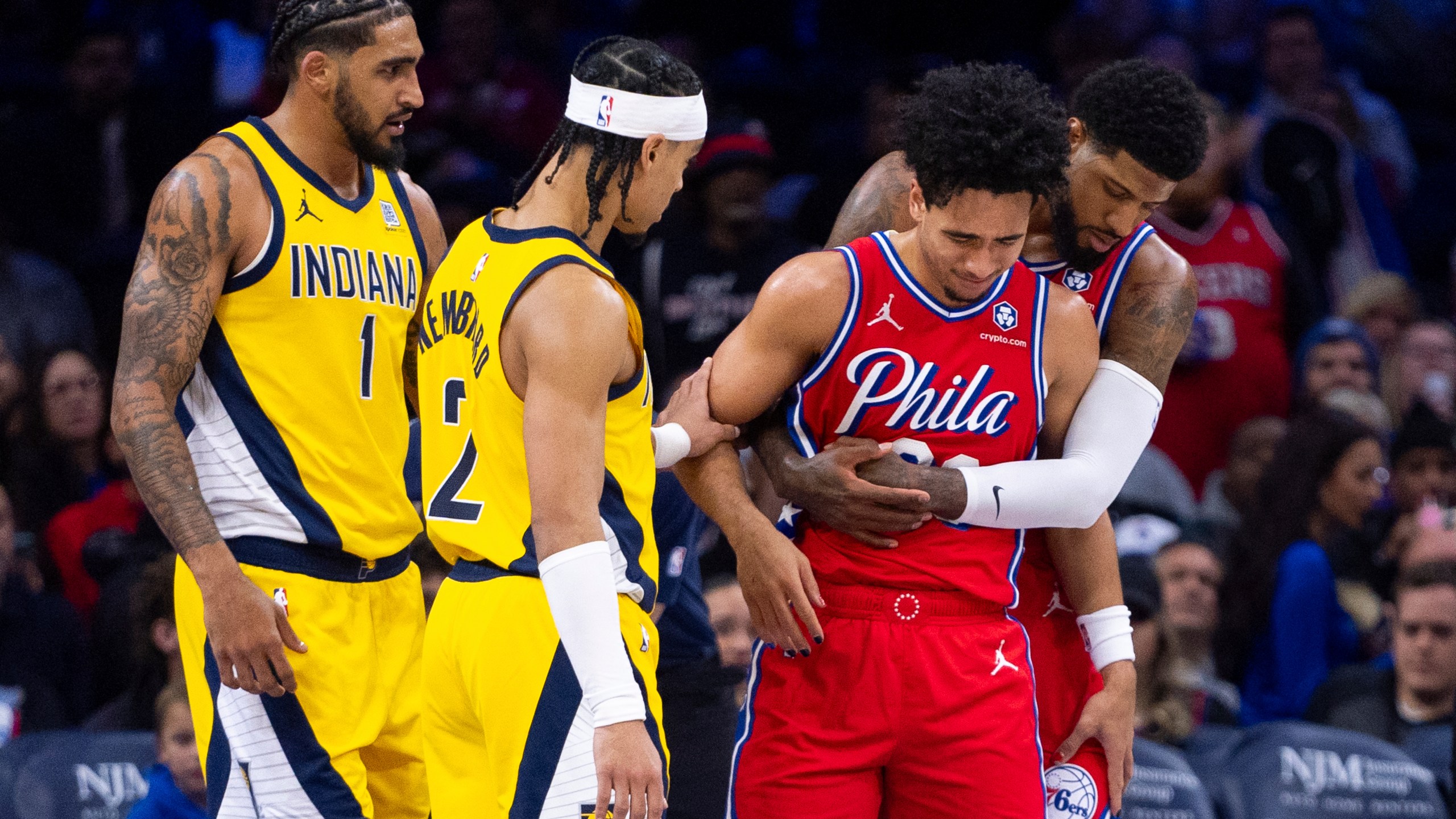 Philadelphia 76ers' Jared McCain, center right, gets helped by Paul George, right, and Indiana Pacers' Andrew Nembhard, center left, after a hard fall to the court during the second half of an NBA basketball game, Friday, Dec. 13, 2024, in Philadelphia. The Pacers won 121-107. (AP Photo/Chris Szagola)