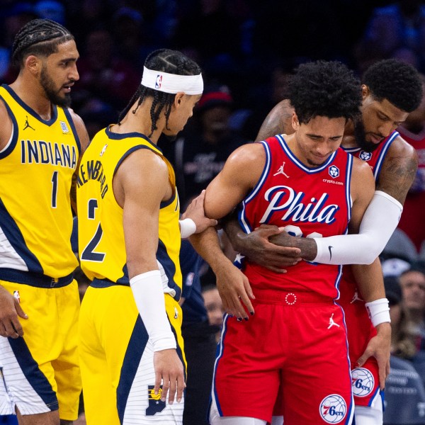 Philadelphia 76ers' Jared McCain, center right, gets helped by Paul George, right, and Indiana Pacers' Andrew Nembhard, center left, after a hard fall to the court during the second half of an NBA basketball game, Friday, Dec. 13, 2024, in Philadelphia. The Pacers won 121-107. (AP Photo/Chris Szagola)