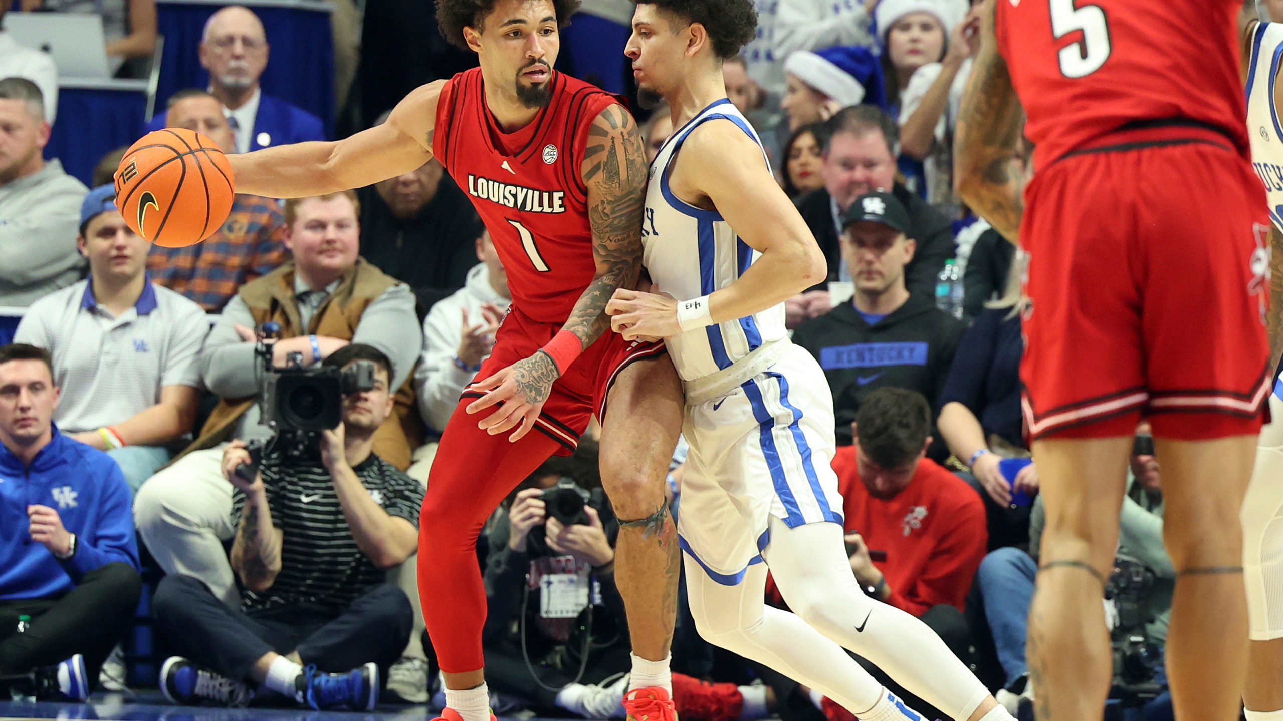 Louisville's J'Vonne Hadley (1) looks for an opening against Kentucky's Koby Brea, center right, during the first half of an NCAA college basketball game in Lexington, Ky., Saturday, Dec. 14, 2024. (AP Photo/James Crisp)