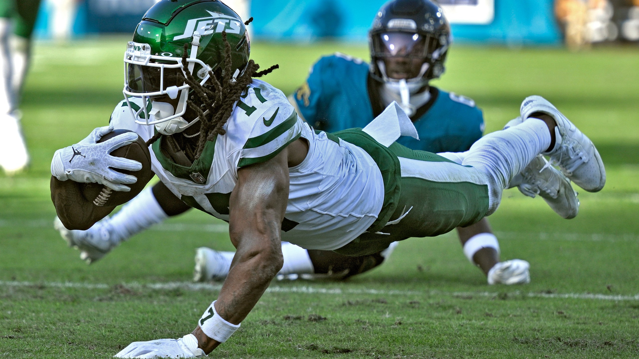 New York Jets wide receiver Davante Adams (17) dives past Jacksonville Jaguars safety Darnell Savage (6) after a catch during the second half of an NFL football game Sunday, Dec. 15, 2024, in Jacksonville, Fla. (AP Photo/Phelan M. Ebenhack)