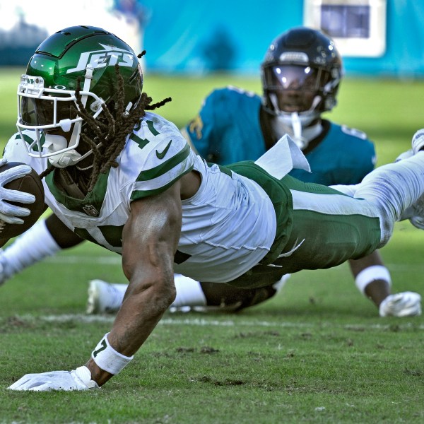 New York Jets wide receiver Davante Adams (17) dives past Jacksonville Jaguars safety Darnell Savage (6) after a catch during the second half of an NFL football game Sunday, Dec. 15, 2024, in Jacksonville, Fla. (AP Photo/Phelan M. Ebenhack)