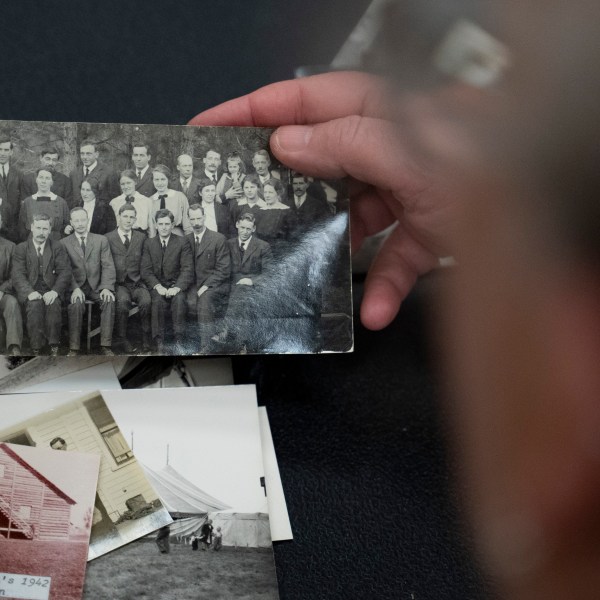 Pam Walton holds a photograph of “Two by Twos” ministers, also referred to as “workers,” at a library Monday, Dec. 9, 2004, in Wailea, Hawaii. Walton uses historic photos and other records to track the movements of spiritual leaders facing allegations of child sexual abuse within the sect. (AP Photo/Mengshin Lin)