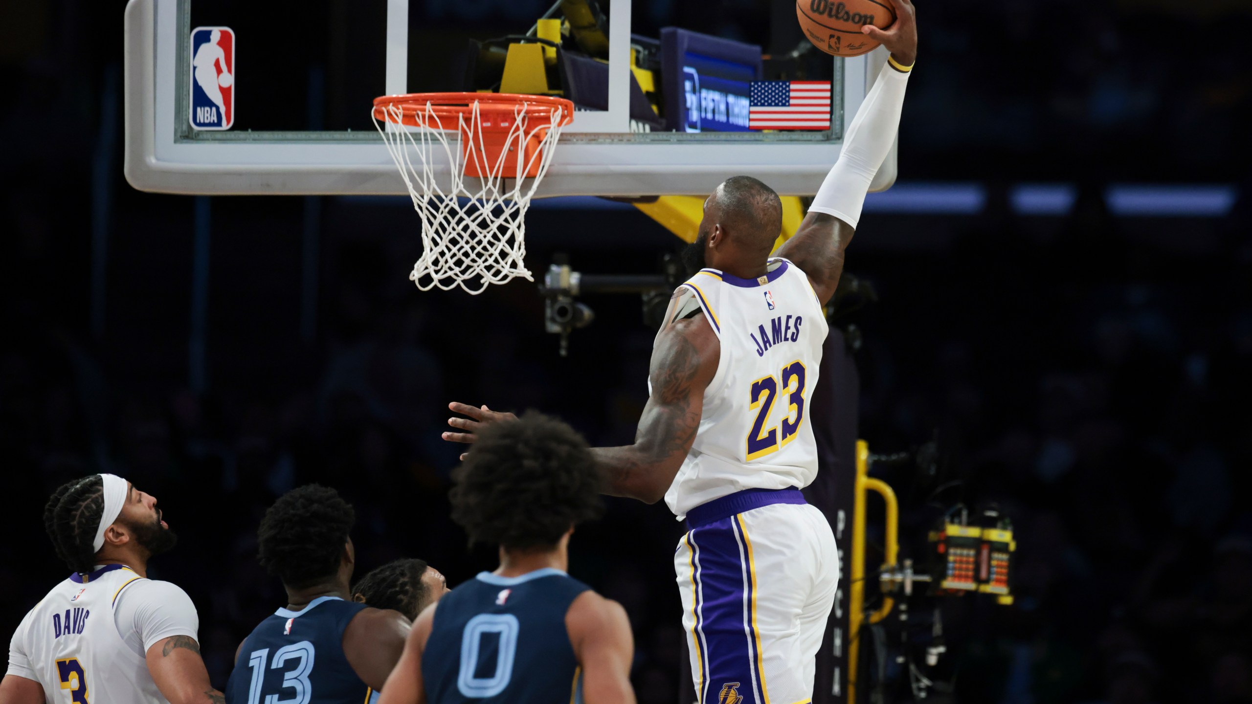 Los Angeles Lakers forward LeBron James (23) dunks the ball as forward Anthony Davis (3), Memphis Grizzlies forward Jaren Jackson Jr. (13) and forward Jaylen Wells (0) watch during the first half of an NBA basketball game, Sunday, Dec. 15, 2024, in Los Angeles. (AP Photo/Jessie Alcheh)