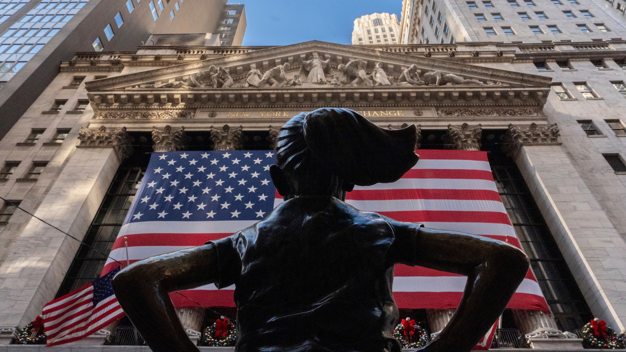 The New York Stock Exchange is shown behind the statue titled "Fearless Girl", Thursday, Dec. 12, 2024, in New York. (AP Photo/Julia Demaree Nikhinson)