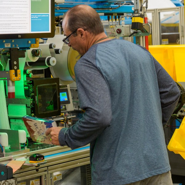 FILE - An employee uses an automated packaging machine to create a made-to-measure bag for a book at Amazon OXR1 fulfillment center in Oxnard, Calif., on Aug. 21, 2024. (AP Photo/Damian Dovarganes, File)