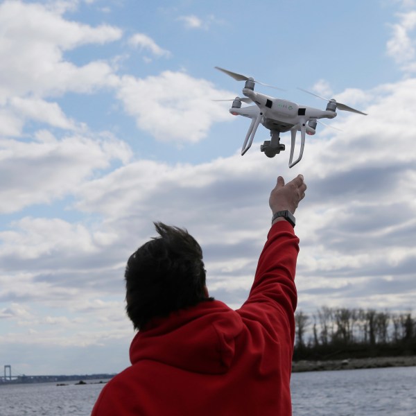 FILE - In this April 29, 2018, file photo, a drone operator helps to retrieve a drone after photographing over Hart Island in New York. (AP Photo/Seth Wenig, File)