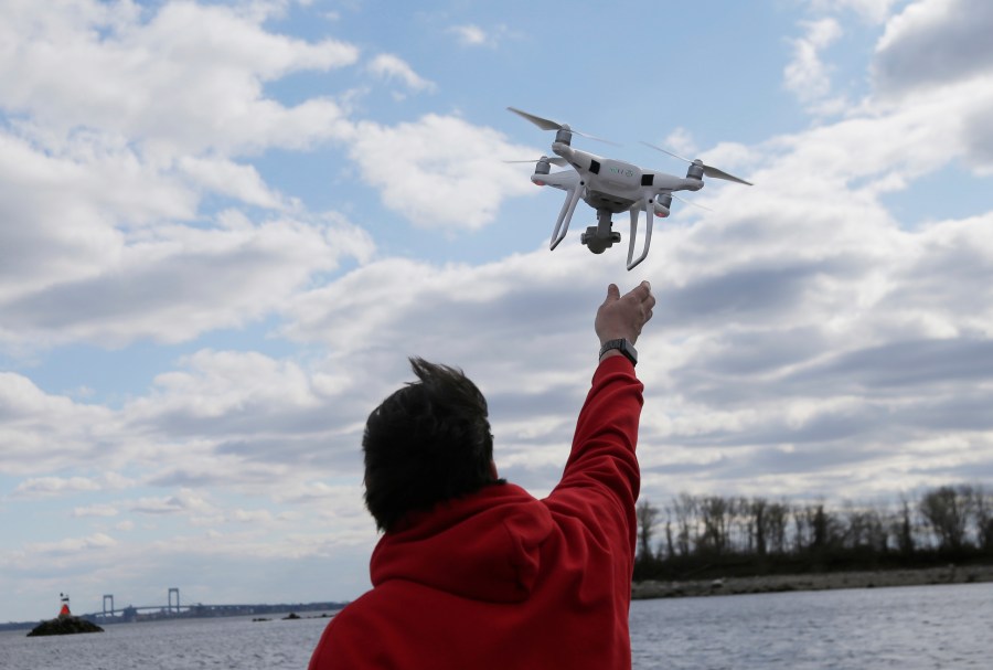 FILE - In this April 29, 2018, file photo, a drone operator helps to retrieve a drone after photographing over Hart Island in New York. (AP Photo/Seth Wenig, File)