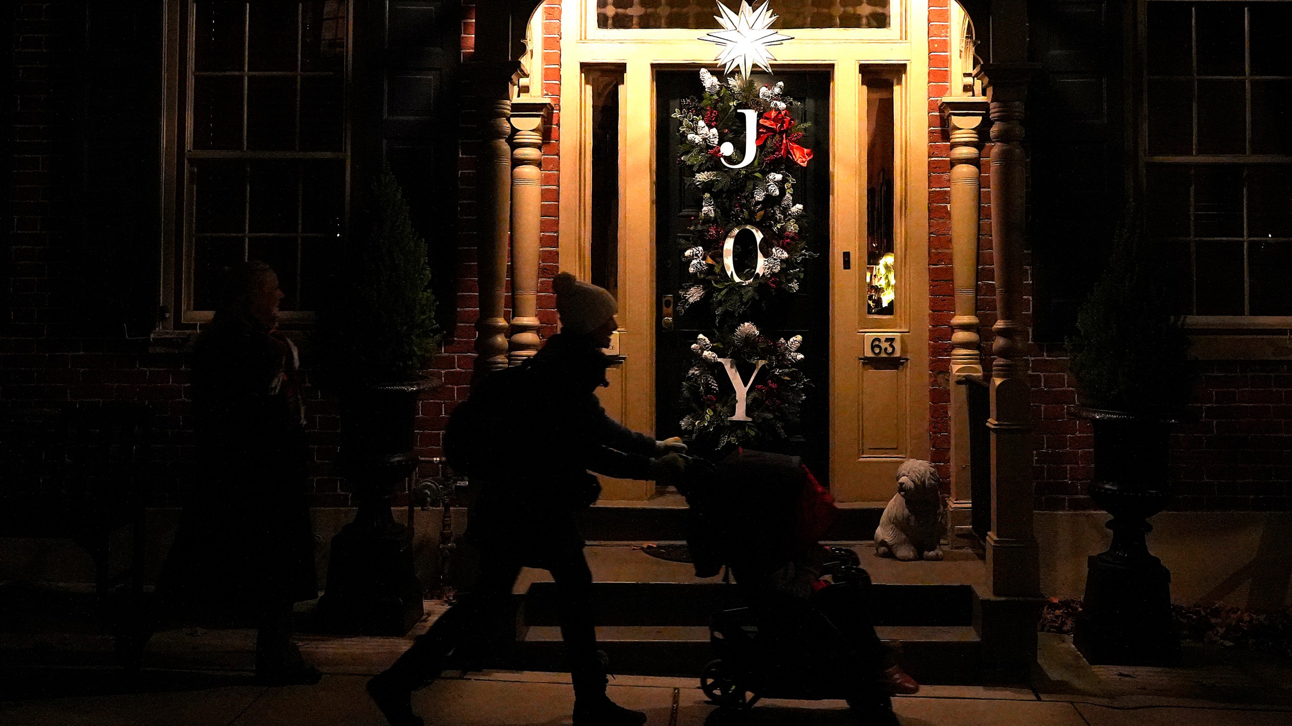 A woman pushes a stroller in front of a house decorated with a Moravian star and Christmas wreaths in Bethlehem, Pa., on Sunday, Dec. 1, 2024. (AP Photo/Luis Andres Henao)